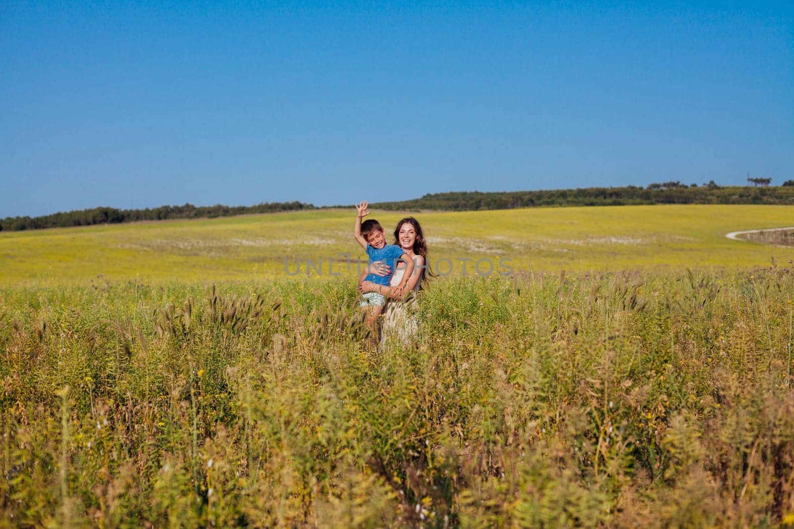 Mother and young son walking in a rural field in summer