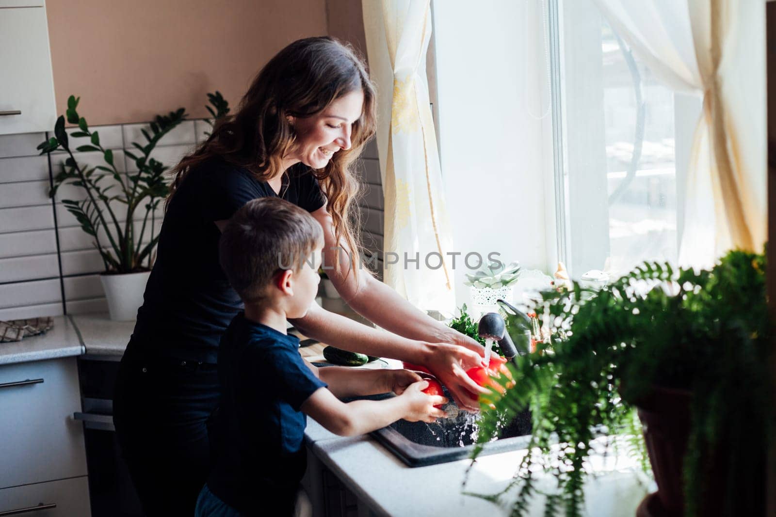 mom and son washing vegetables in kitchen for food