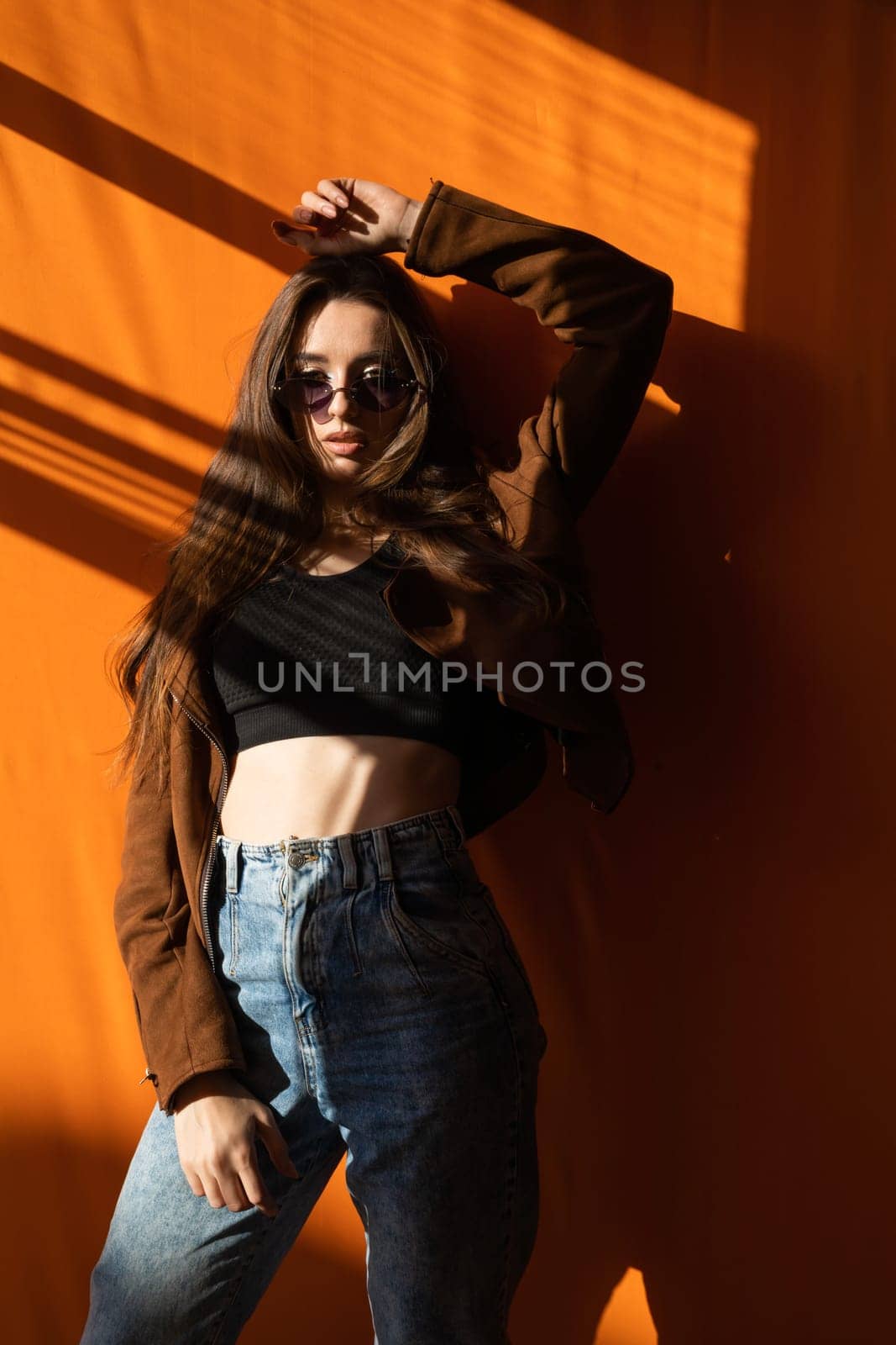 Beautiful woman in sunglasses in orange room by window