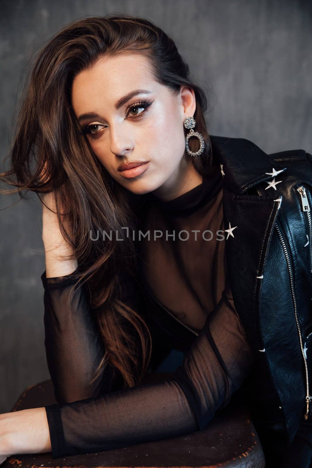 Beautiful fashionable woman in black leather dress in gray room interior