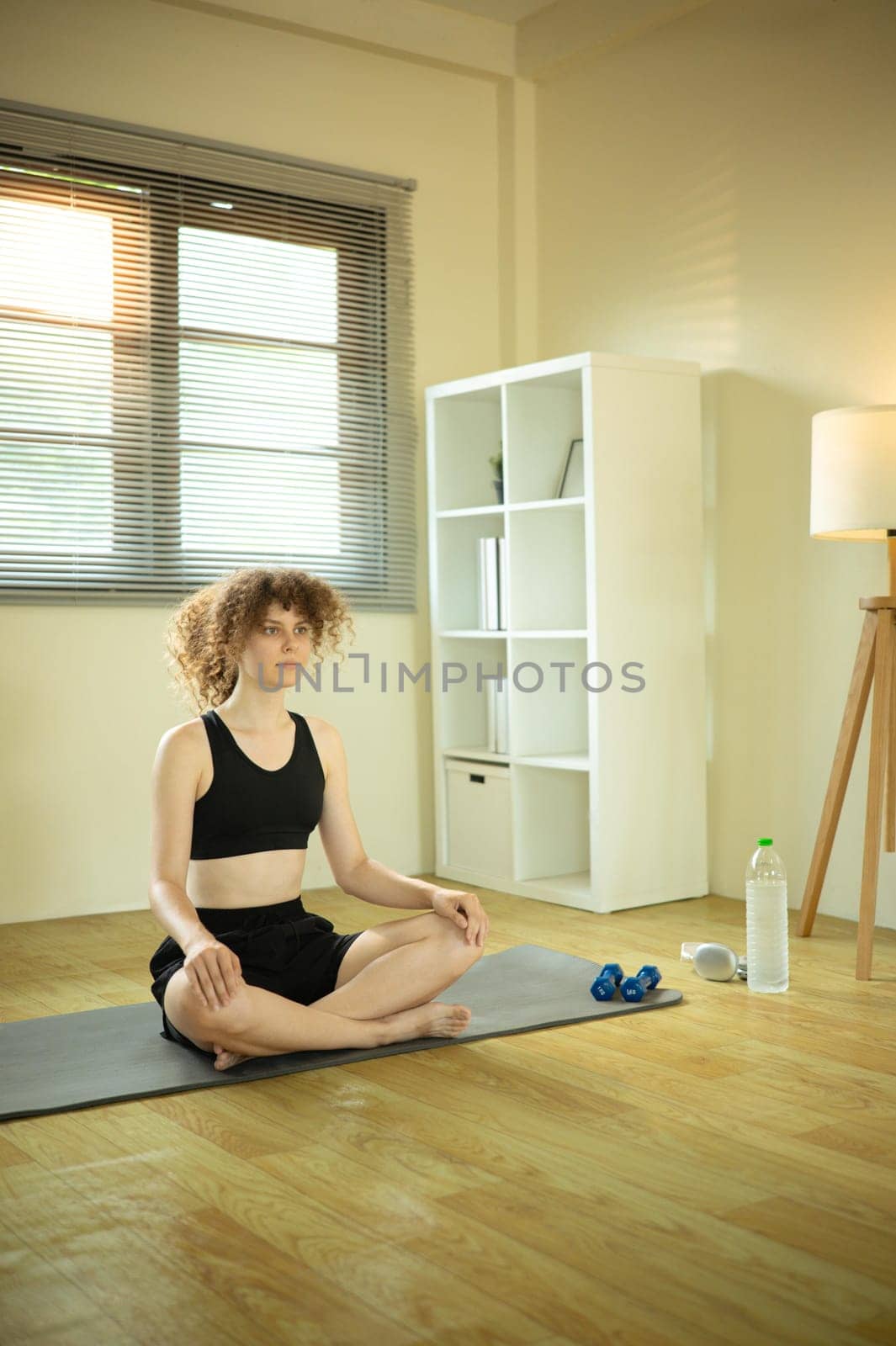 Young Russian woman with curly hair practicing yoga at home.