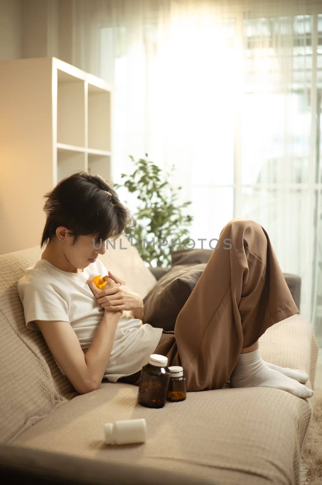 Man dealing with emotional pain and depression at home surrounded by medication.