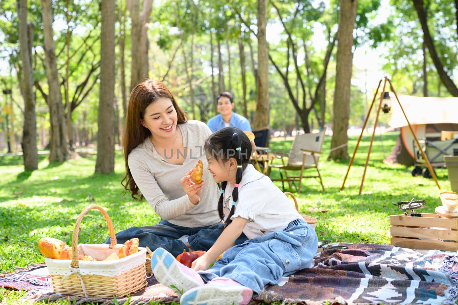 Mother and daughter sharing food during a family camping trip.