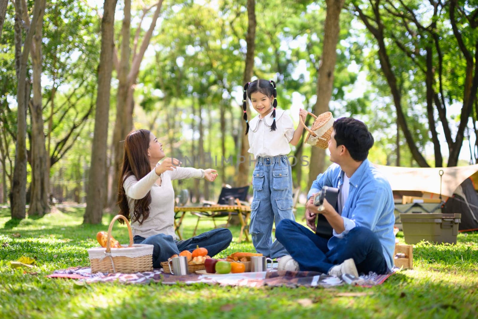 Cheerful family camping outdoors, sharing snacks and spending quality time near tent in the park..