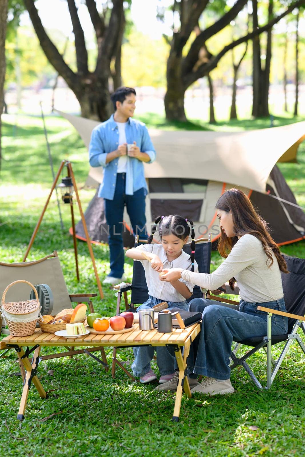 Mother and daughter enjoying a relaxing breakfast at a campsite.