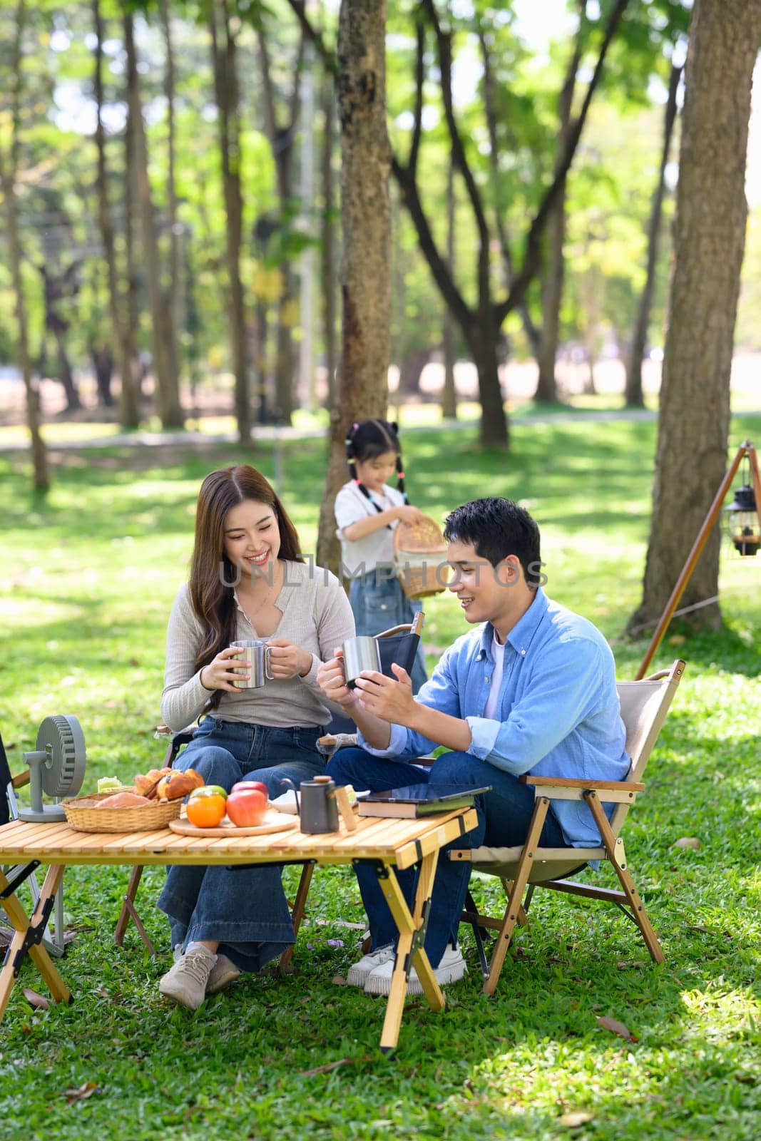 Cheerful parents enjoying a warm drink together at campsite.