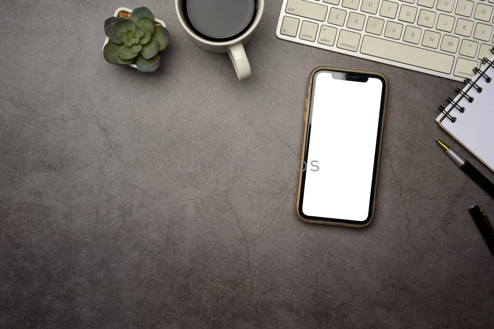 Flat lay of smartphone with blank screen on dark modern desk.
