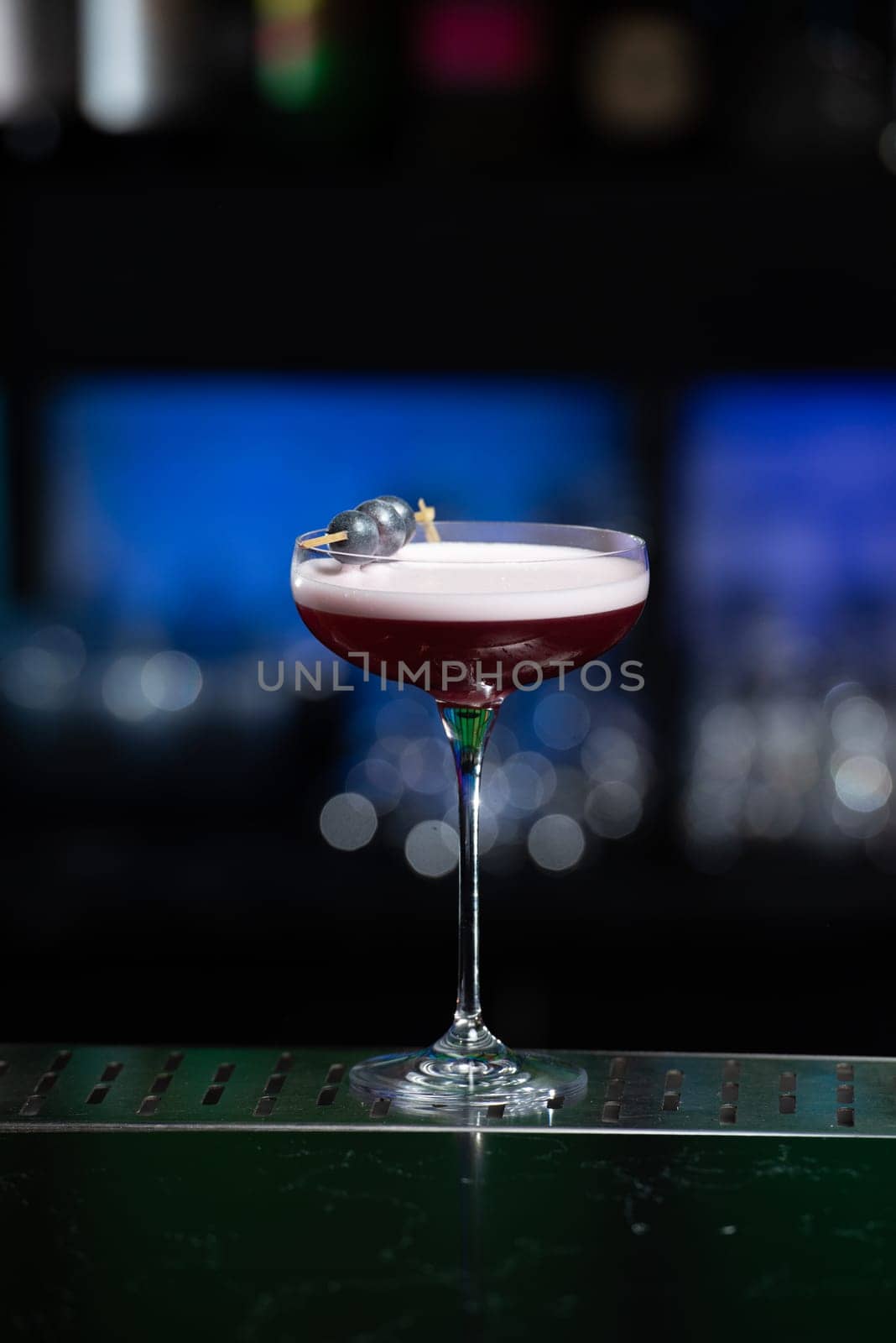 The blurred background features dark tones with hints of green and white bokeh lights, suggesting a stylish bar setting
