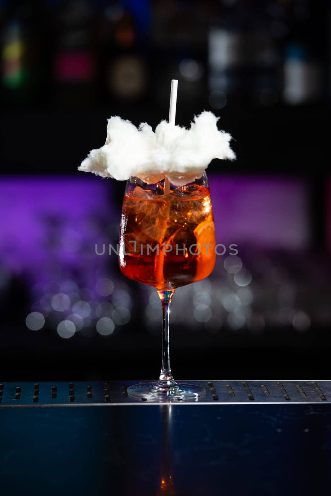 The background features a blurred mix of deep blue and purple hues, suggesting a modern bar or lounge atmosphere