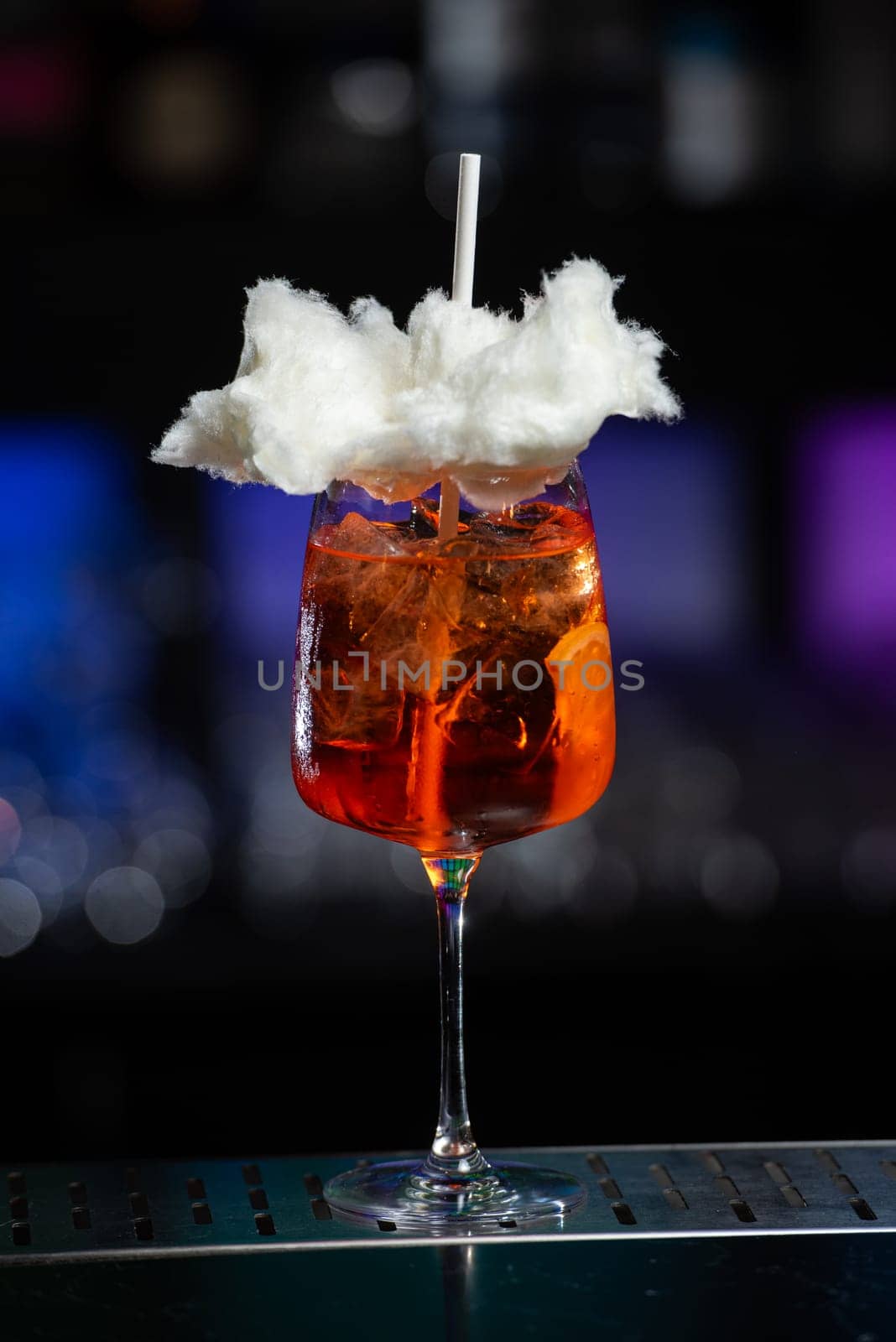 The background features a blurred mix of deep blue and purple hues, suggesting a modern bar or lounge atmosphere