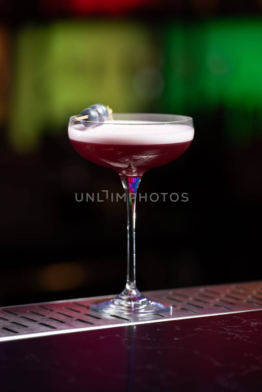 The blurred background features dark tones with hints of green and white bokeh lights, suggesting a stylish bar setting