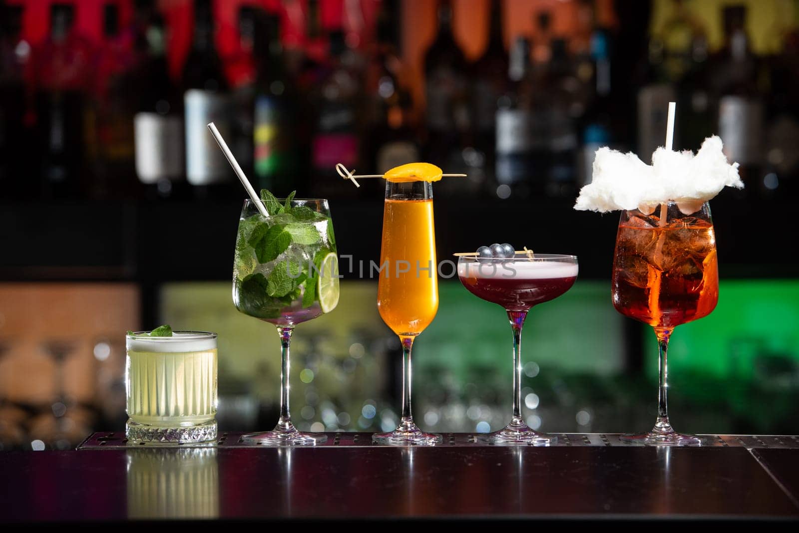 row of various colourfull alcoholic cocktails on a bar desk. Glasses of differen shapes on a fancy background