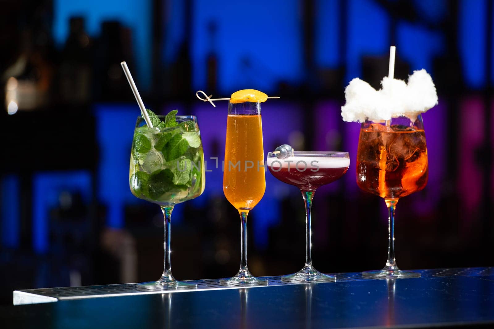 The blurred background suggests a vibrant nightlife setting with various lights and bottles. Selective focus