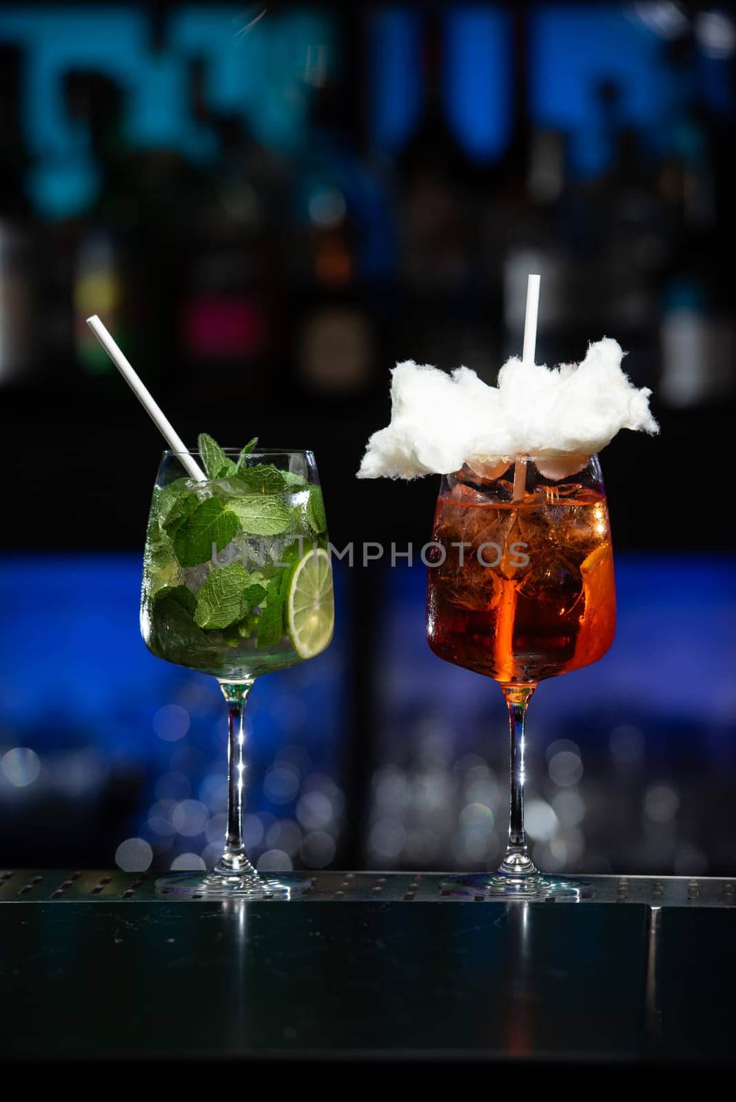 A blurred backdrop of red, green, and black suggests a lively bar or club setting.