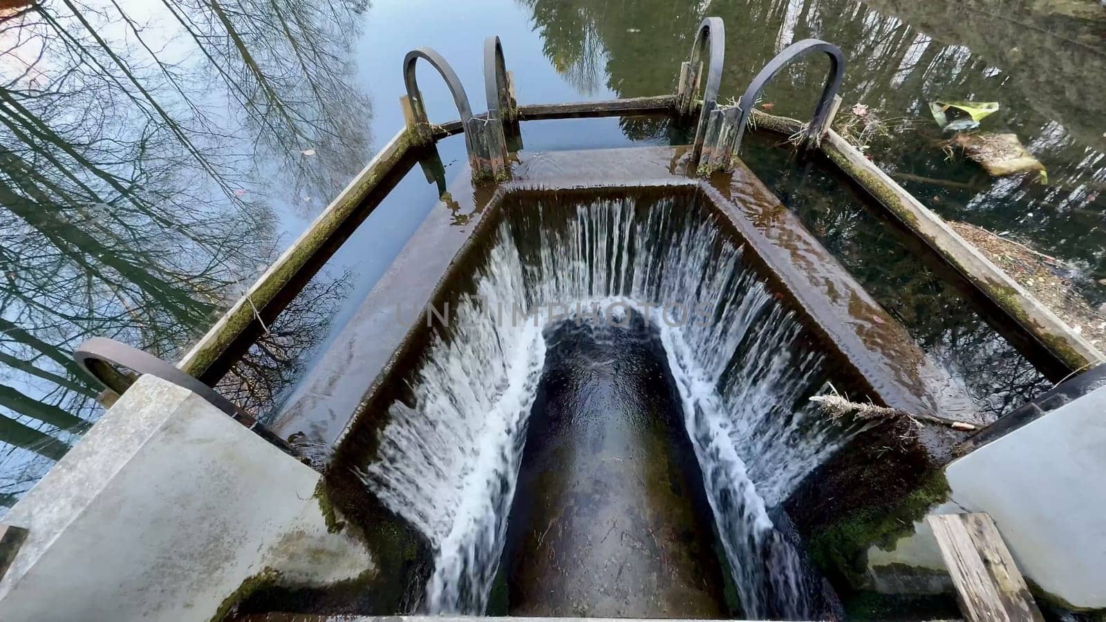 Capture the mesmerizing flow of water through a treatment inlet, surrounded by natures reflections