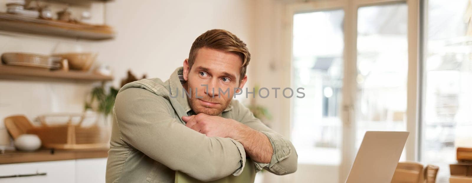 Vertical portrait of handsome masculine man, sitting on chair, looking aside, waiting for an order in coffee shop.