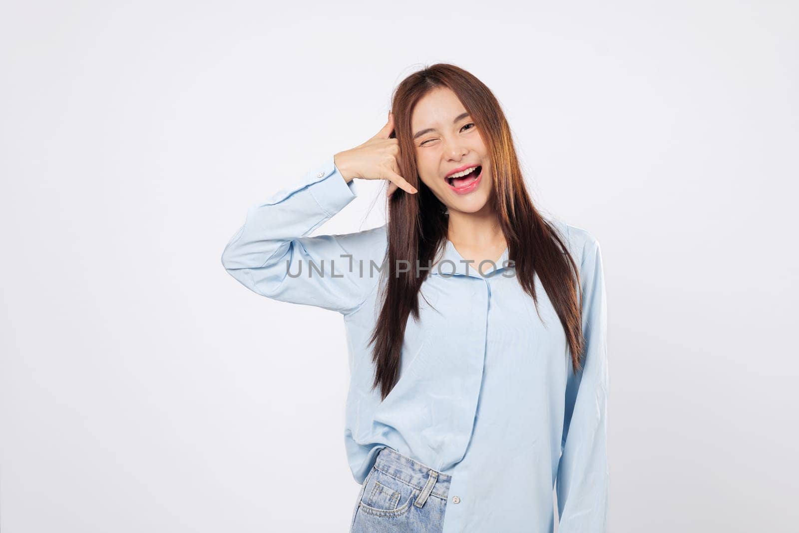 Call me gesture from cheerful woman, second woman winking uses hand as phone with fingers by face, both showing fun and flirty expressions isolated in white studio background setting.