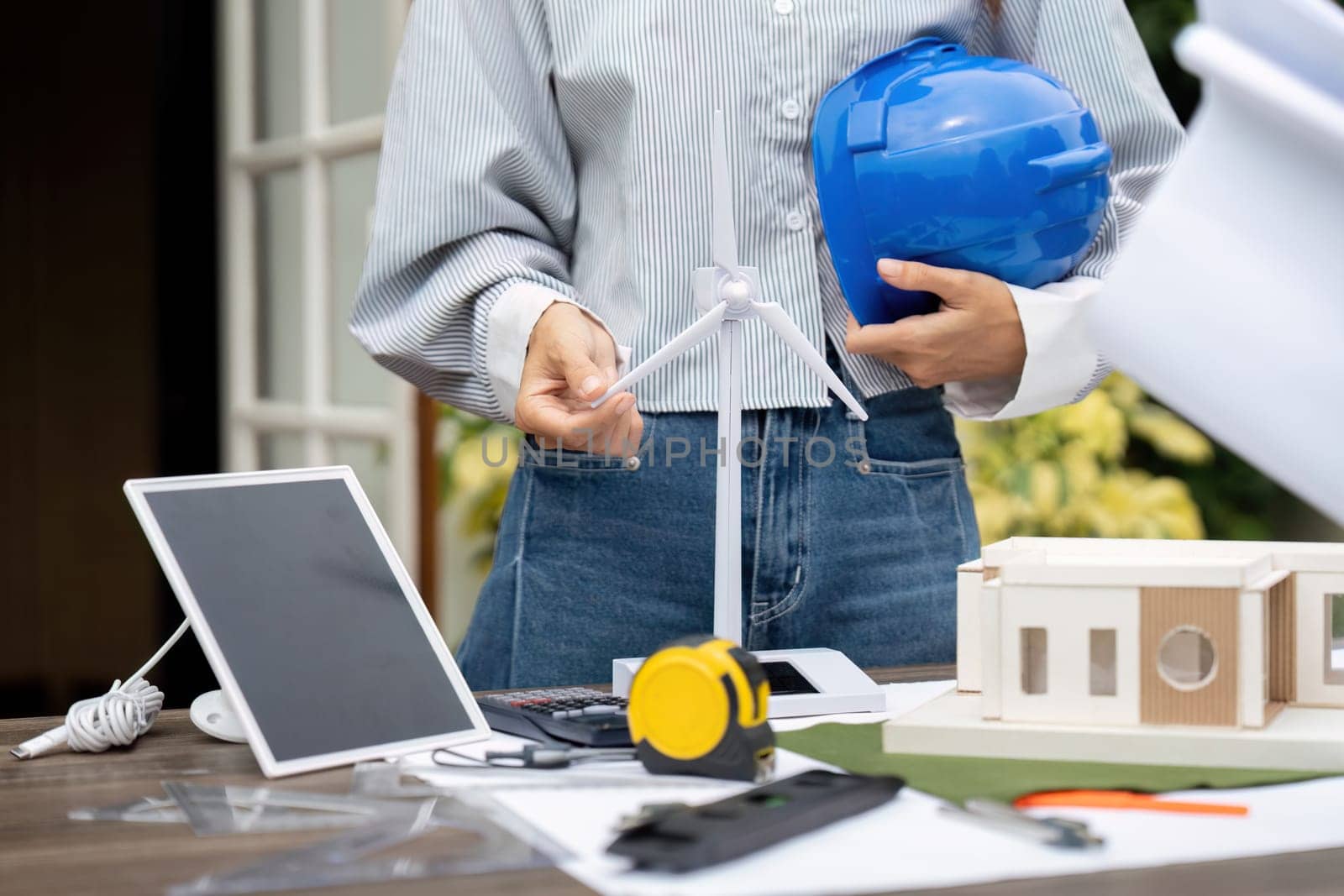 An engineer prepares a sustainable house project using a model, illustrating the commitment to eco-friendly design and renewable energy solutions.