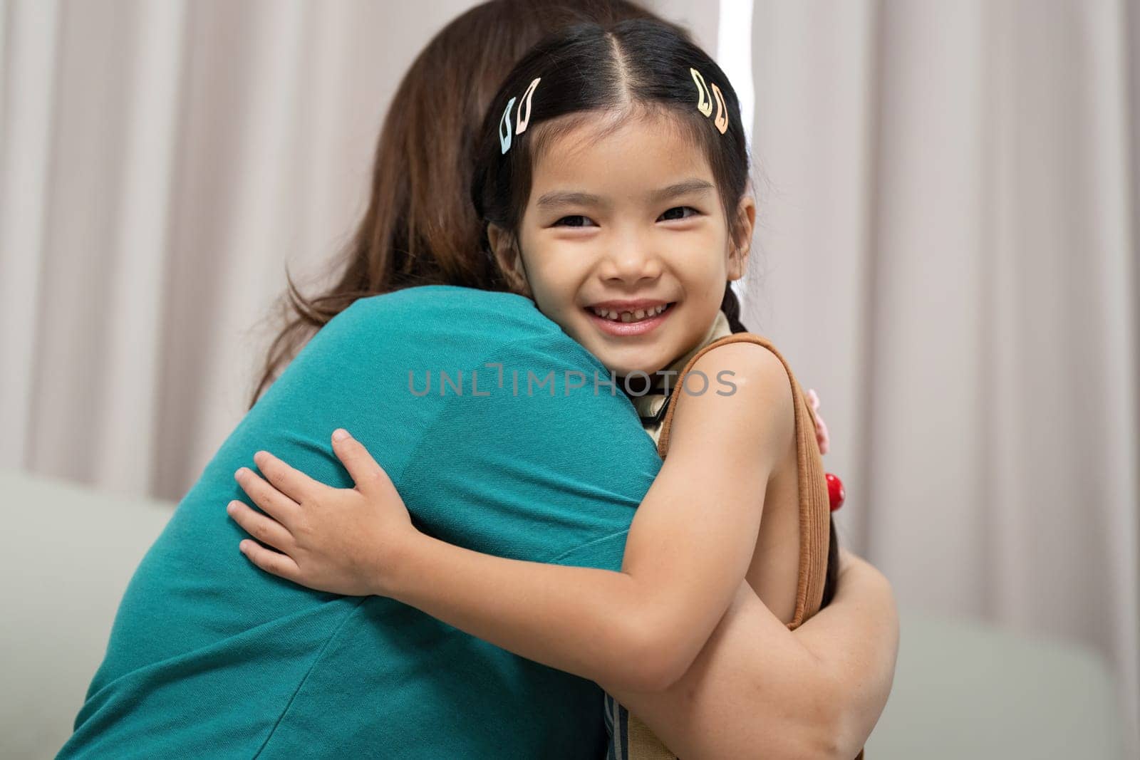 A joyful moment captures a mother hugging her daughter, radiating affection and love in a cozy indoor setting.