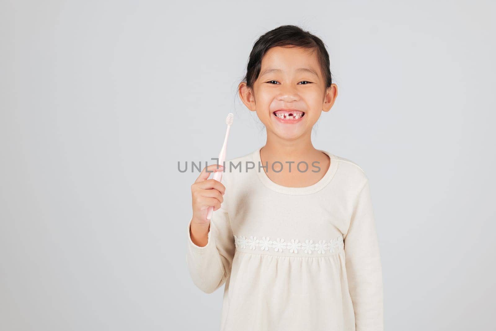 A kid with a missing tooth holds a toothbrush happily. The dentist discusses tooth loss, helping children learn a good dental care routine for healthy teeth. isolated white background