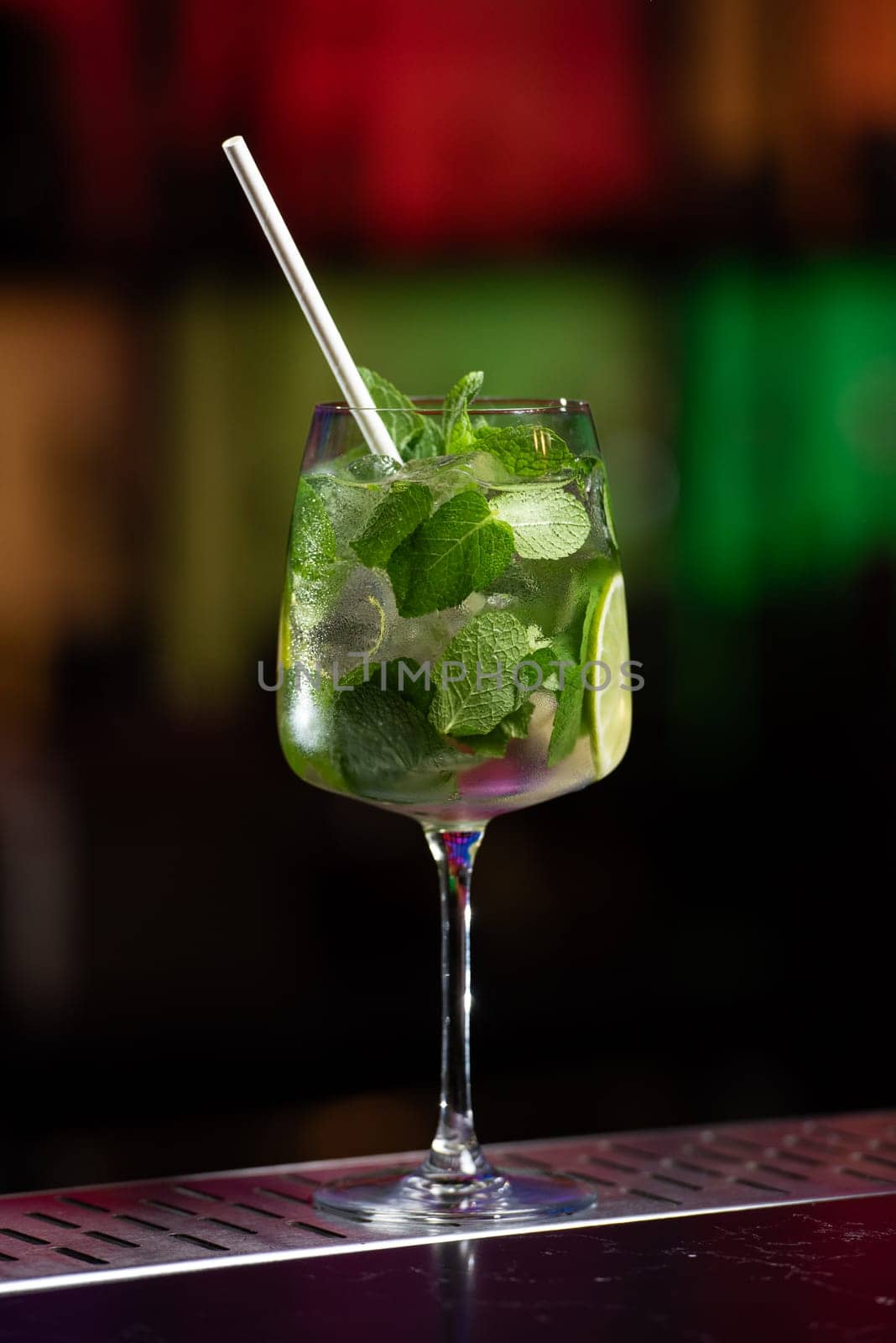 The blurred background features a mix of red, blue, and purple lights, suggesting a vibrant bar atmosphere