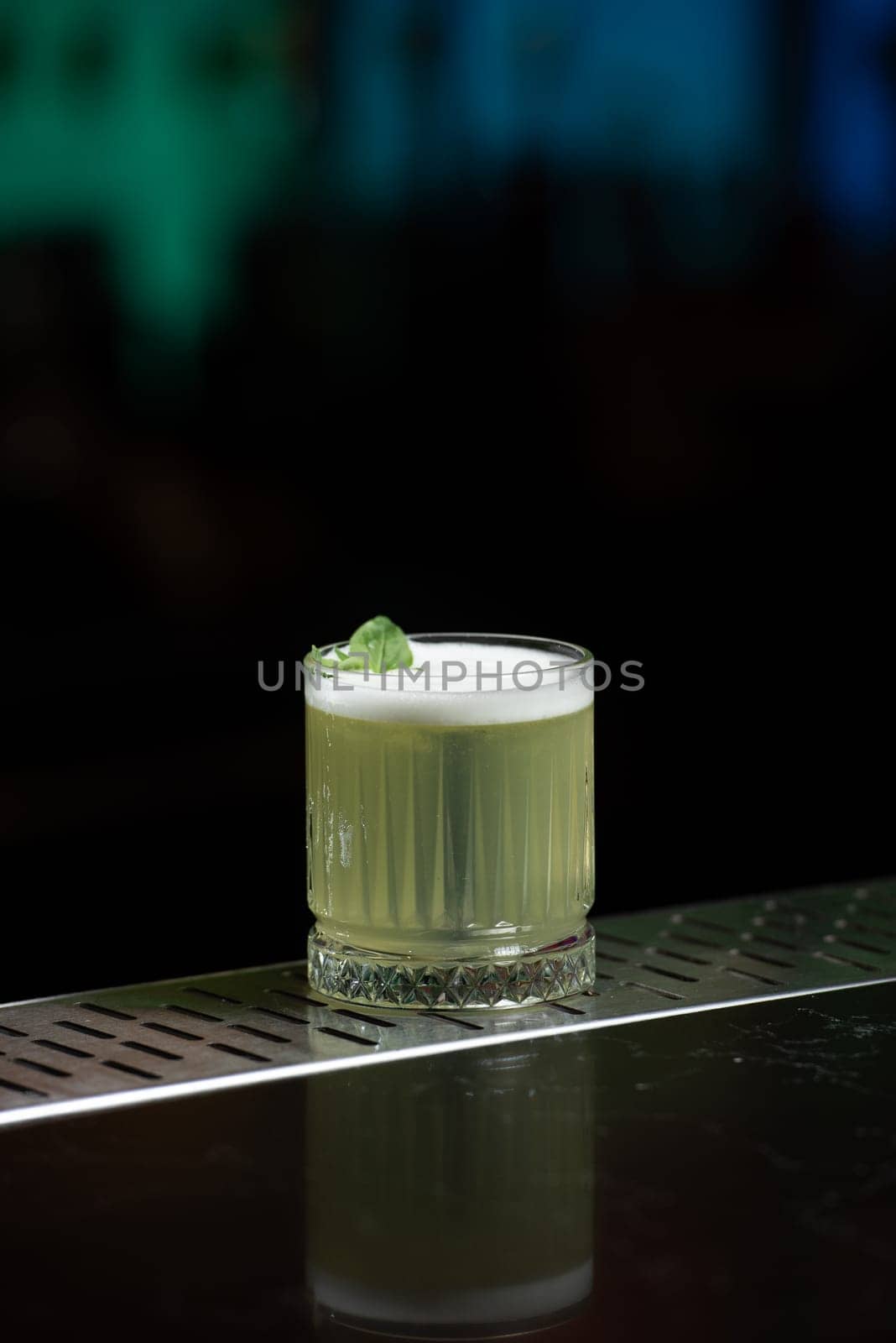 The blurred background features hues of blue and purple with bokeh lights, a stylish bar