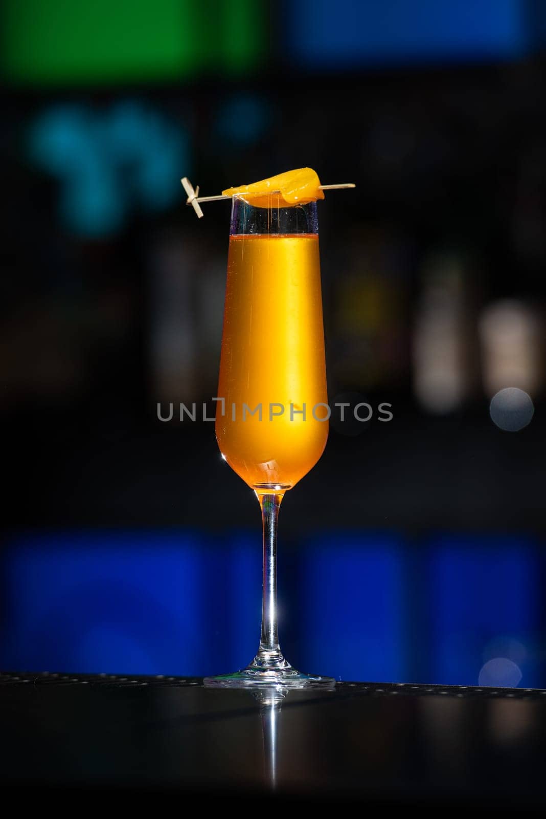 The blurred background features a colorful mix of red, purple, and green, suggesting a lively bar or event setting