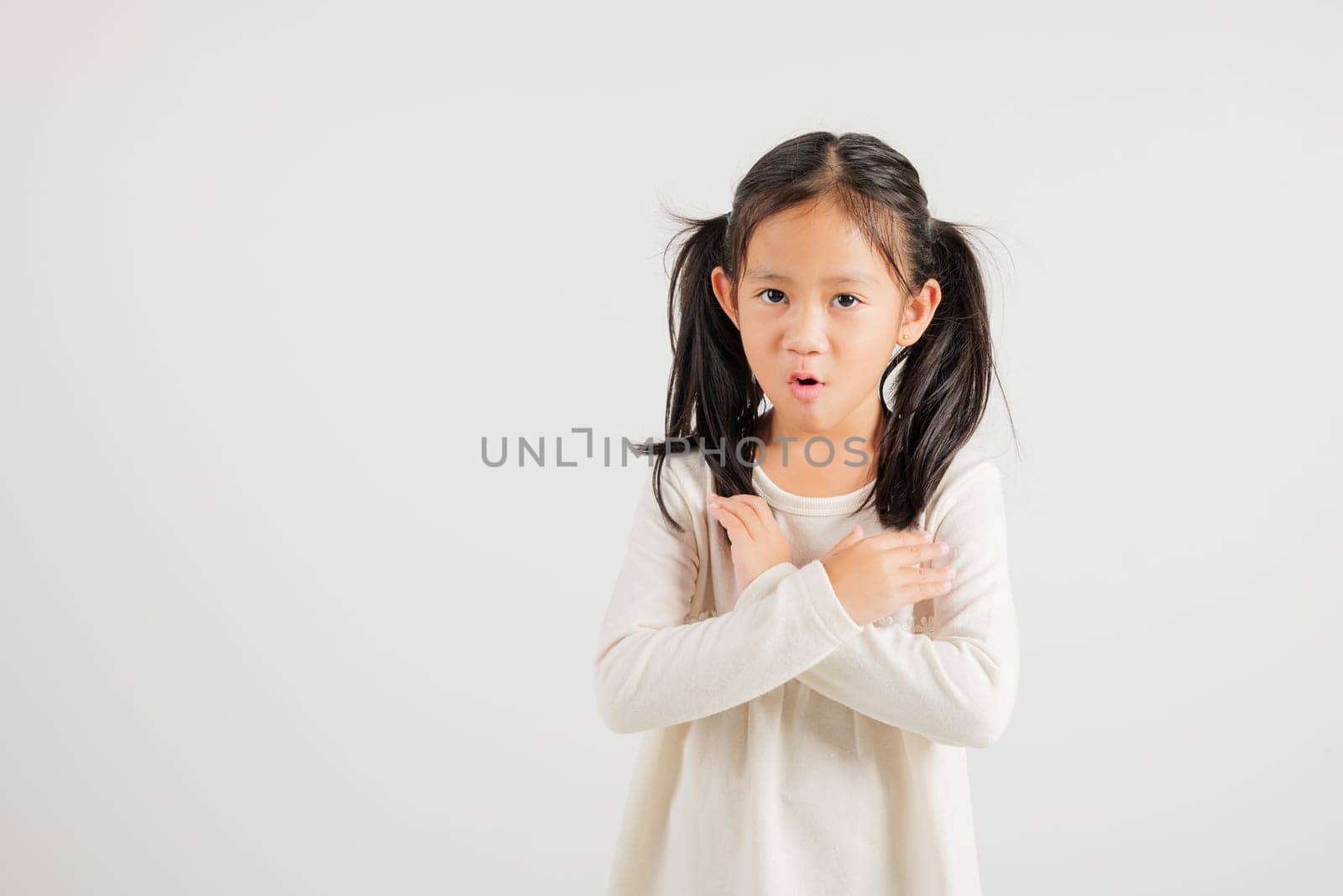 Portrait Asian young kid girl unhappy or confident standing holding two cross arms say no X sign, studio shot isolated white background, Thai kindergarten child pose reject gesture with copy space