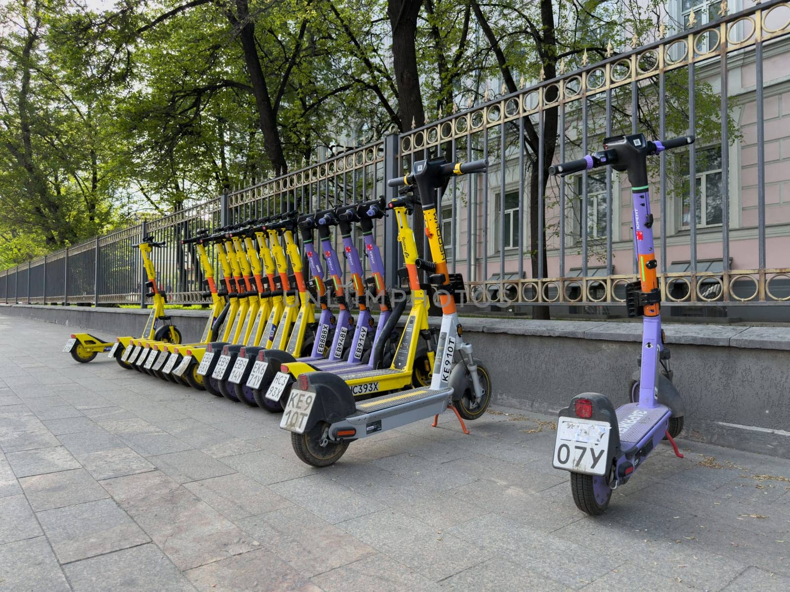 Moscow, Russia, April 24, 2025: Row of parked rental electric scooters from multiple brands lined up on city sidewalk, ready for urban mobility and shared transportation services
