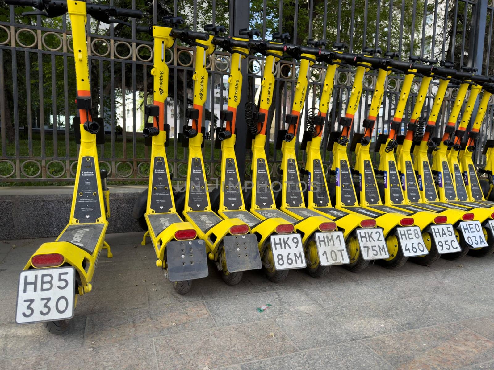 Moscow, Russia, April 24, 2025: Line of Yandex Go yellow electric scooters parked by sidewalk, representing urban mobility service by major Russian tech company in central Moscow