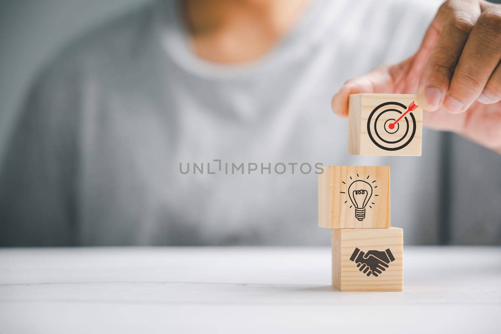 Wood block stacking by hand, symbolizing the implementation of a business strategy and action plan. Targeting the business concept. Conceptual image of success and growth.