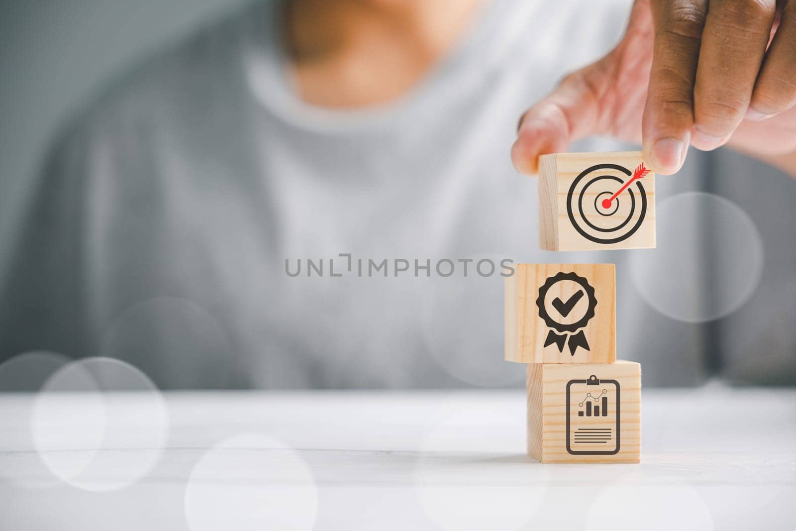 Hand displaying a wooden block cube with an icon, representing company strategy development. Conceptual image of success and business goals.