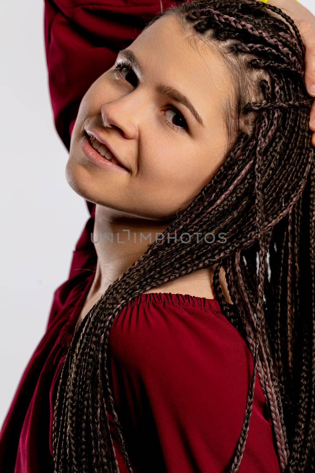 A cheerful and vibrant young woman proudly showcases her intricate braided hairstyle, radiating confidence and style