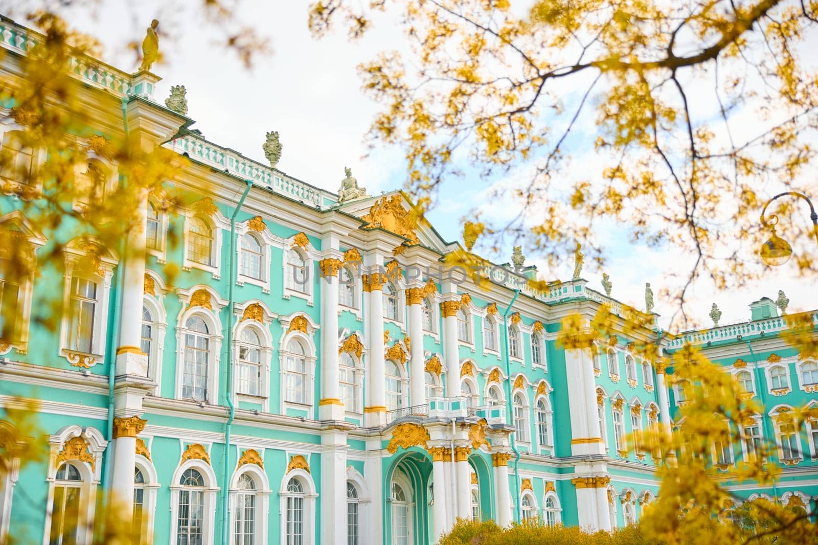 the incredibly picturesque facade of the Winter Palace through the branches of trees on a clear spring day, the heritage of Russia, the most famous landmark of St. Petersburg, the museum. High quality photo