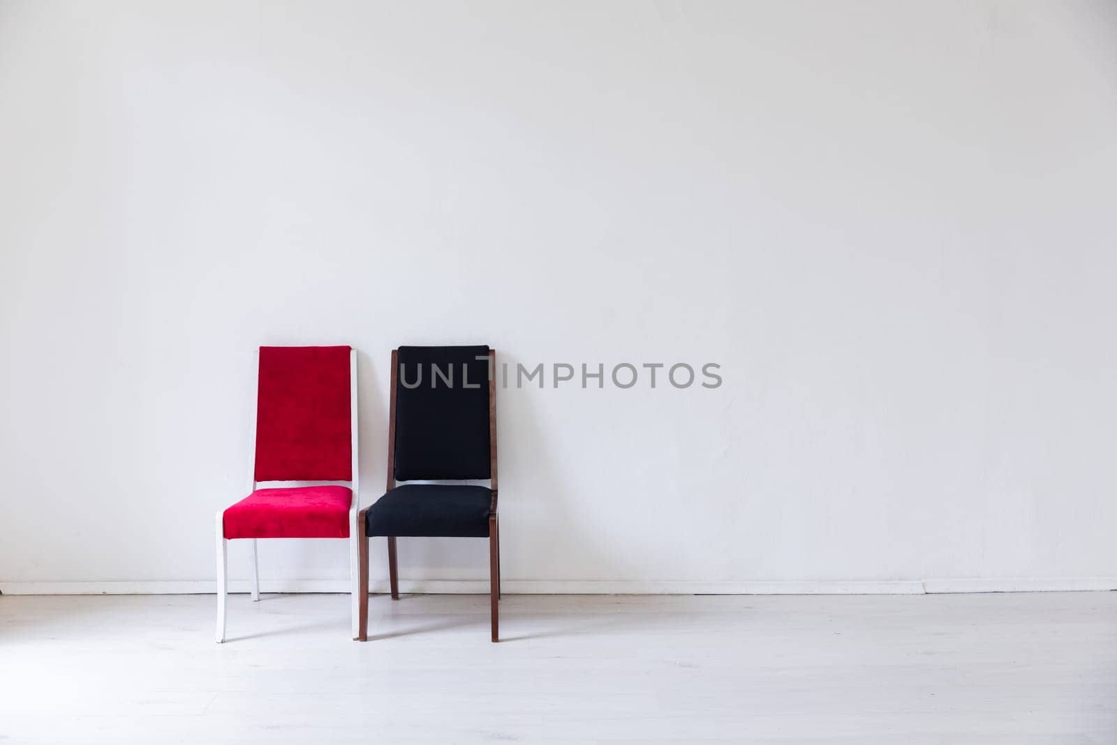 Two old chairs red and black in the interior of a white room