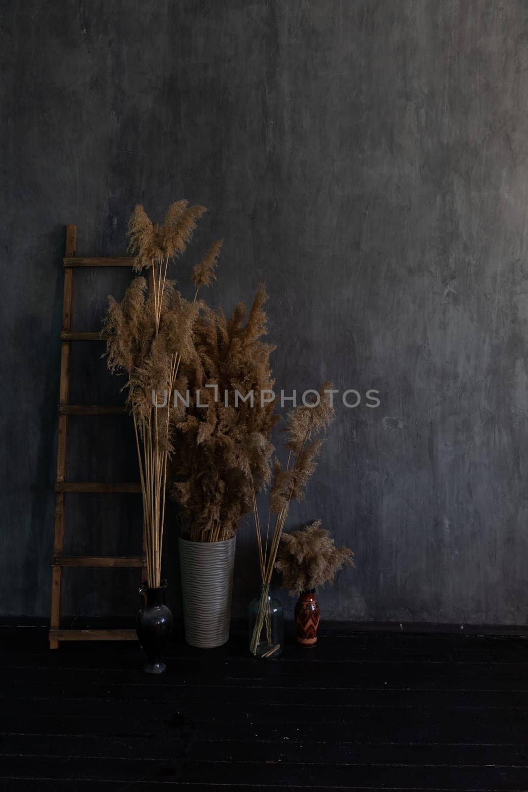Vase with dry flowers and staircase in the interior of a dark gray room