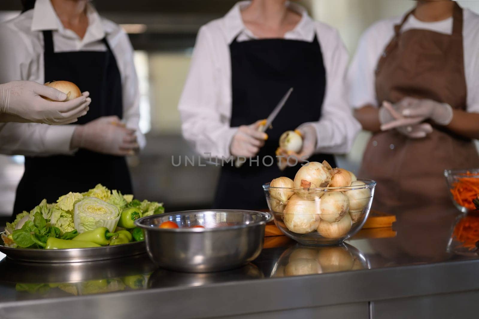 Group of cooking school students preparing fresh vegetables during a culinary class.