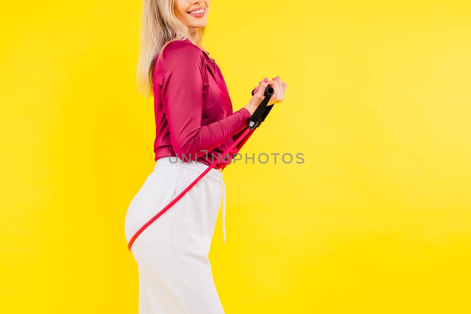 Sports woman in fashion sportswear exercising with elastic band in a studio