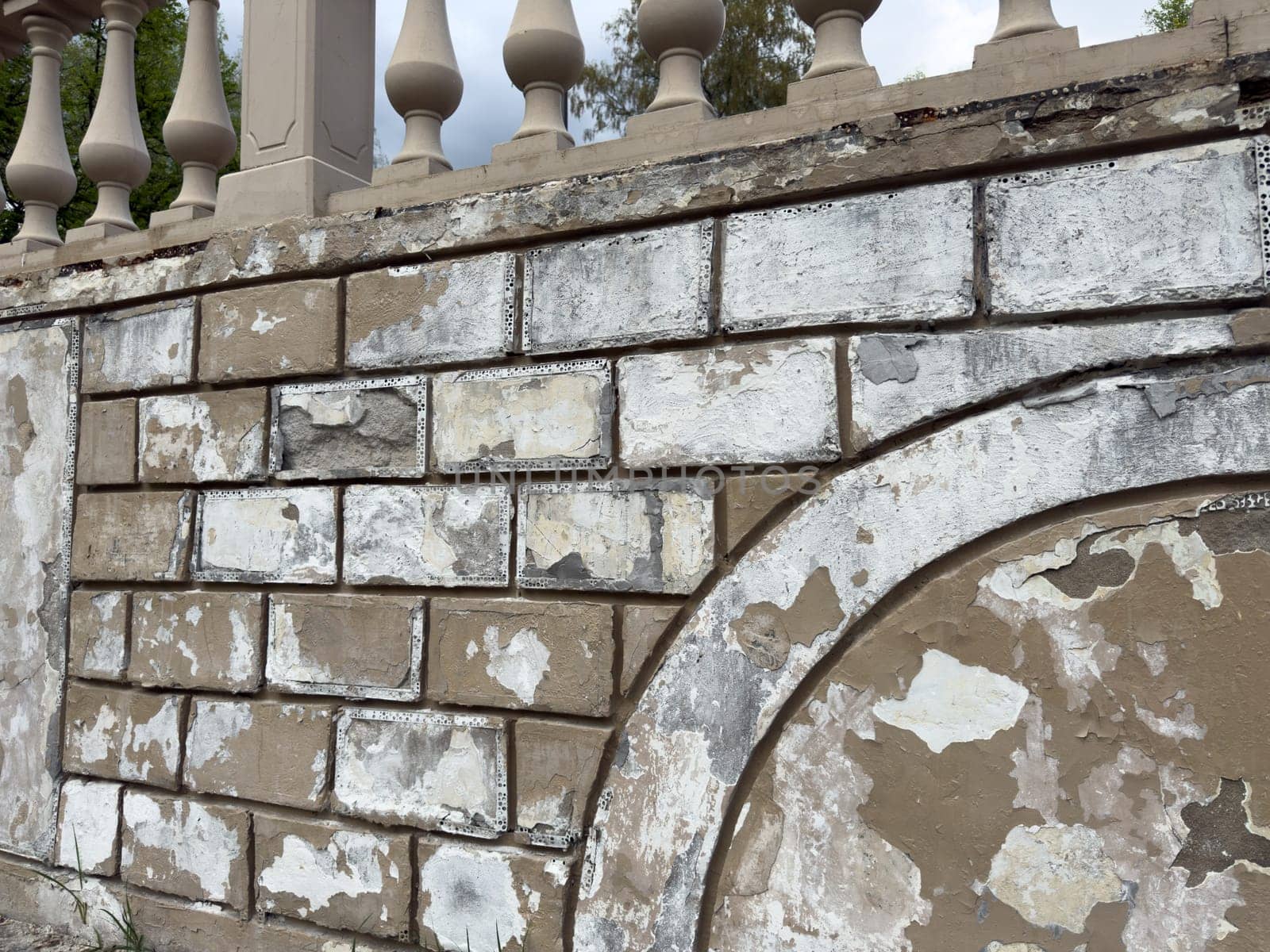 Old textured brick wall with crumbling plaster and flaking paint shows deep signs of wear and weathering, creating a visually rich architectural background suitable for texture or design use