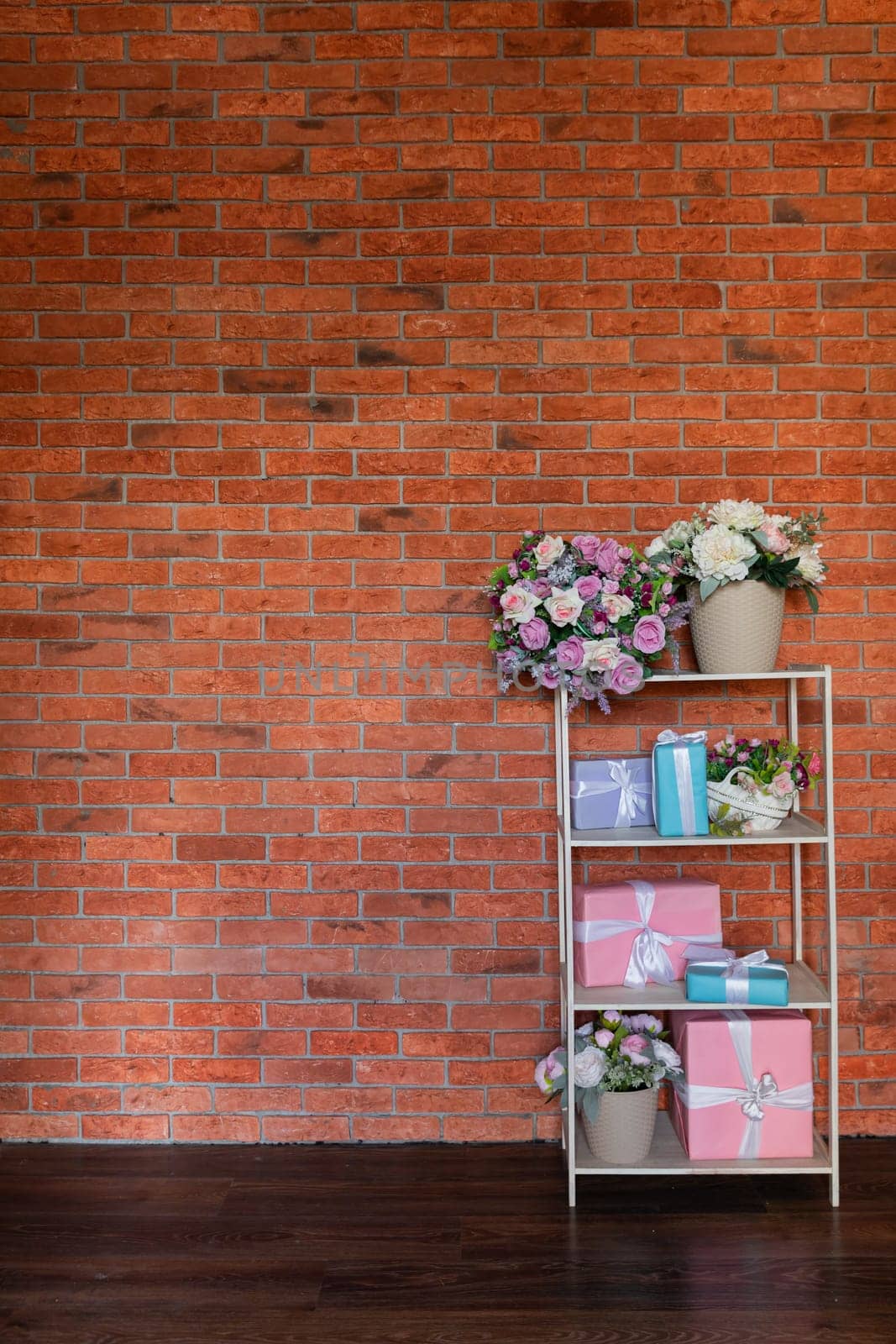 Gift shelves with a vase of flowers in the interior of a room with a brick wall