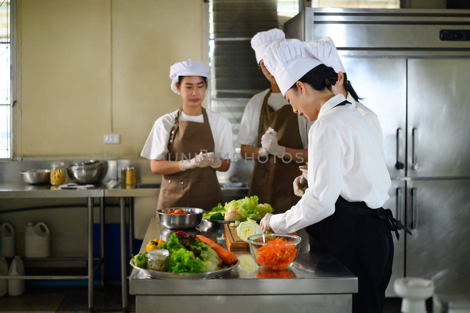 Cooking students attentively watching their teacher demonstrate food preparation techniques.