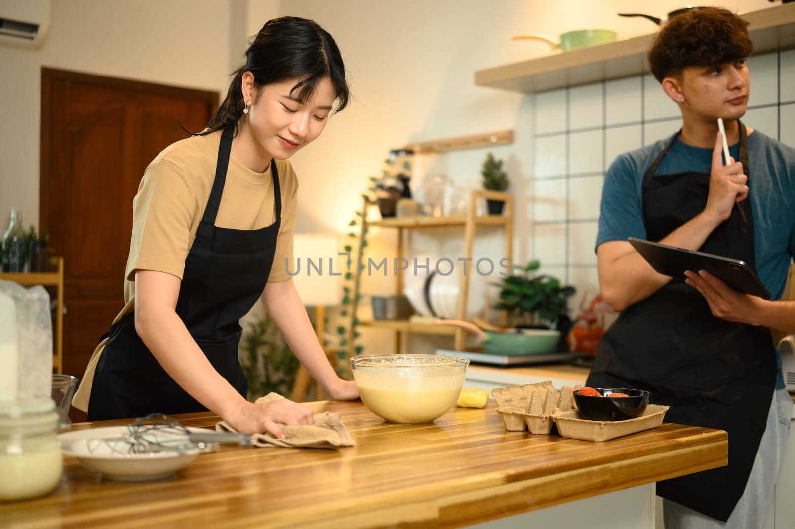 Happy couple preparing pancake batter together in a cozy kitchen.