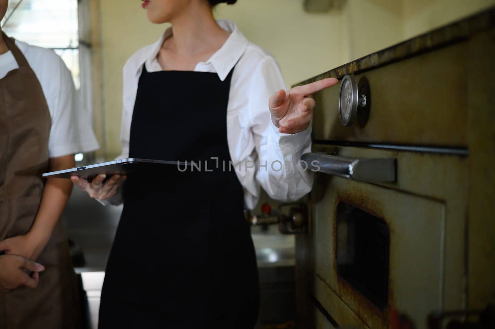 Chef teacher explains temperature control using a commercial oven during culinary class.