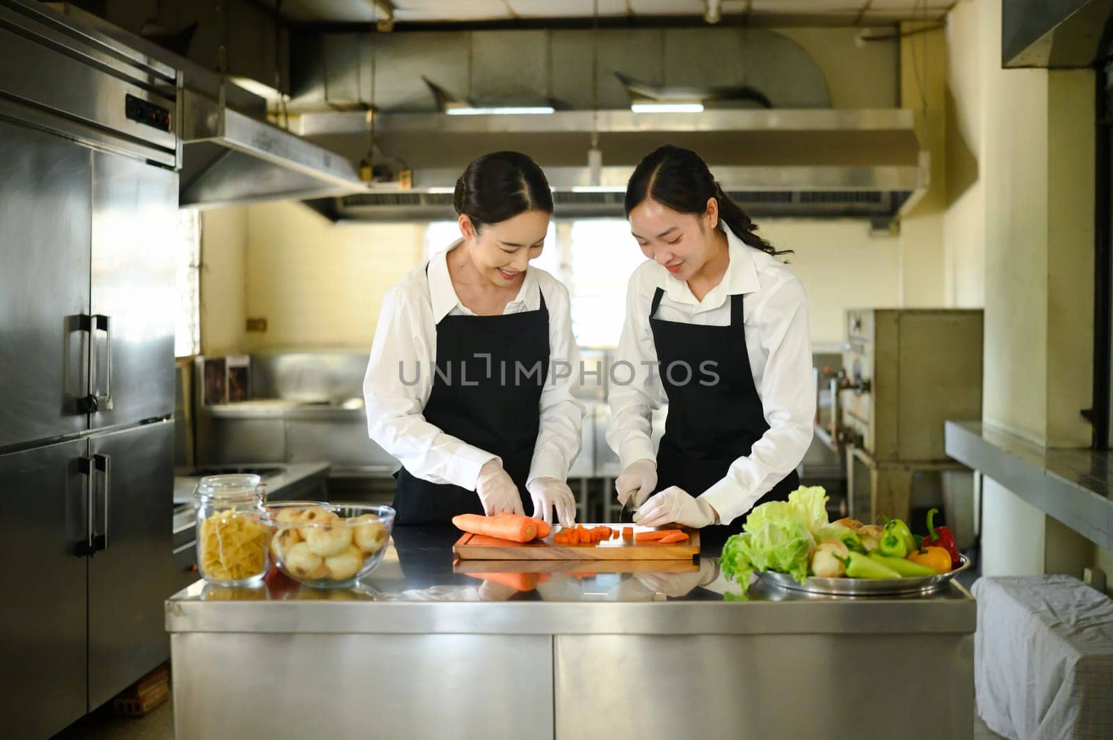 Culinary instructor guiding a student through carrot slicing during a practical cooking class.