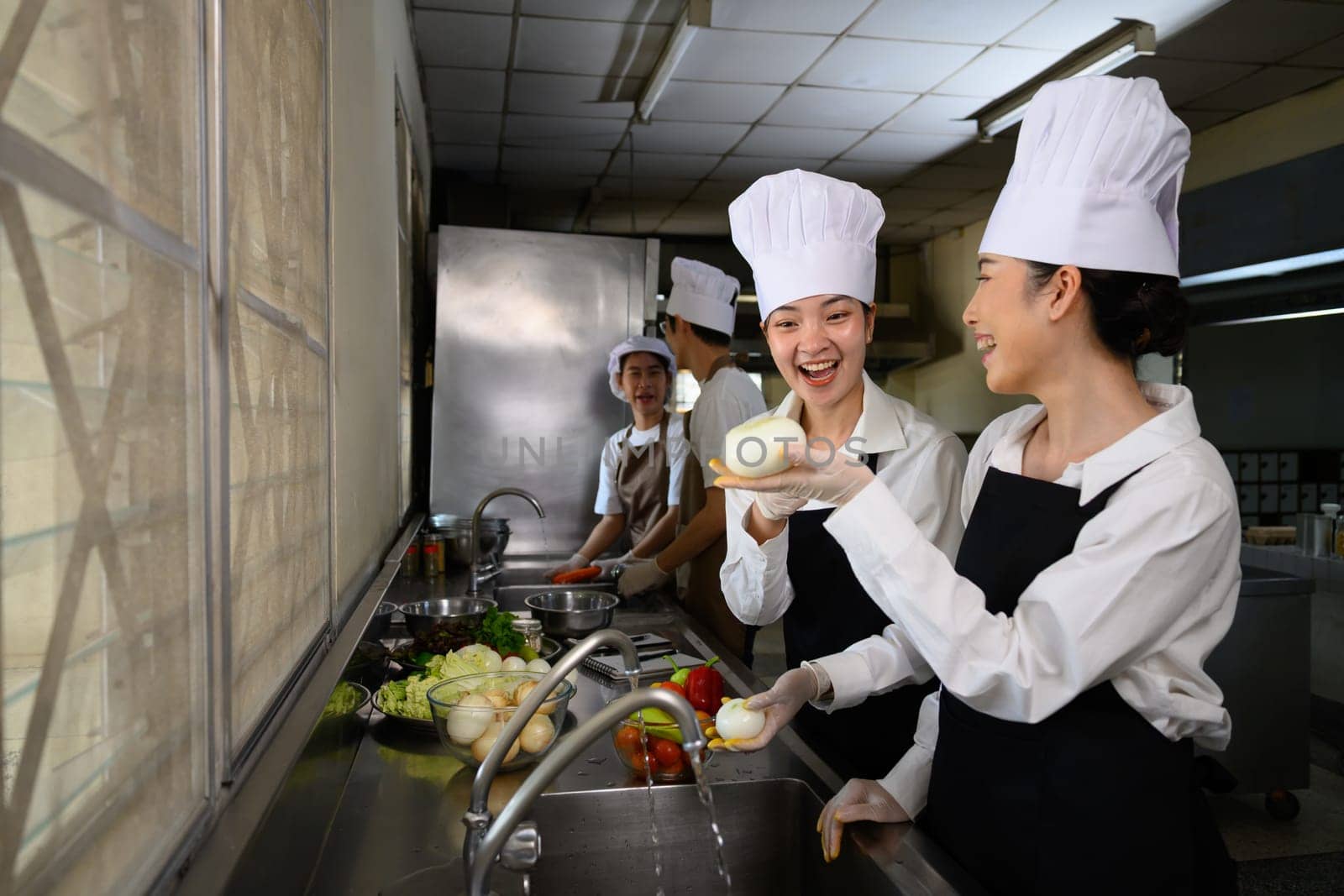 Smiling young chefs learning kitchen hygiene and teamwork in a professional cooking school.