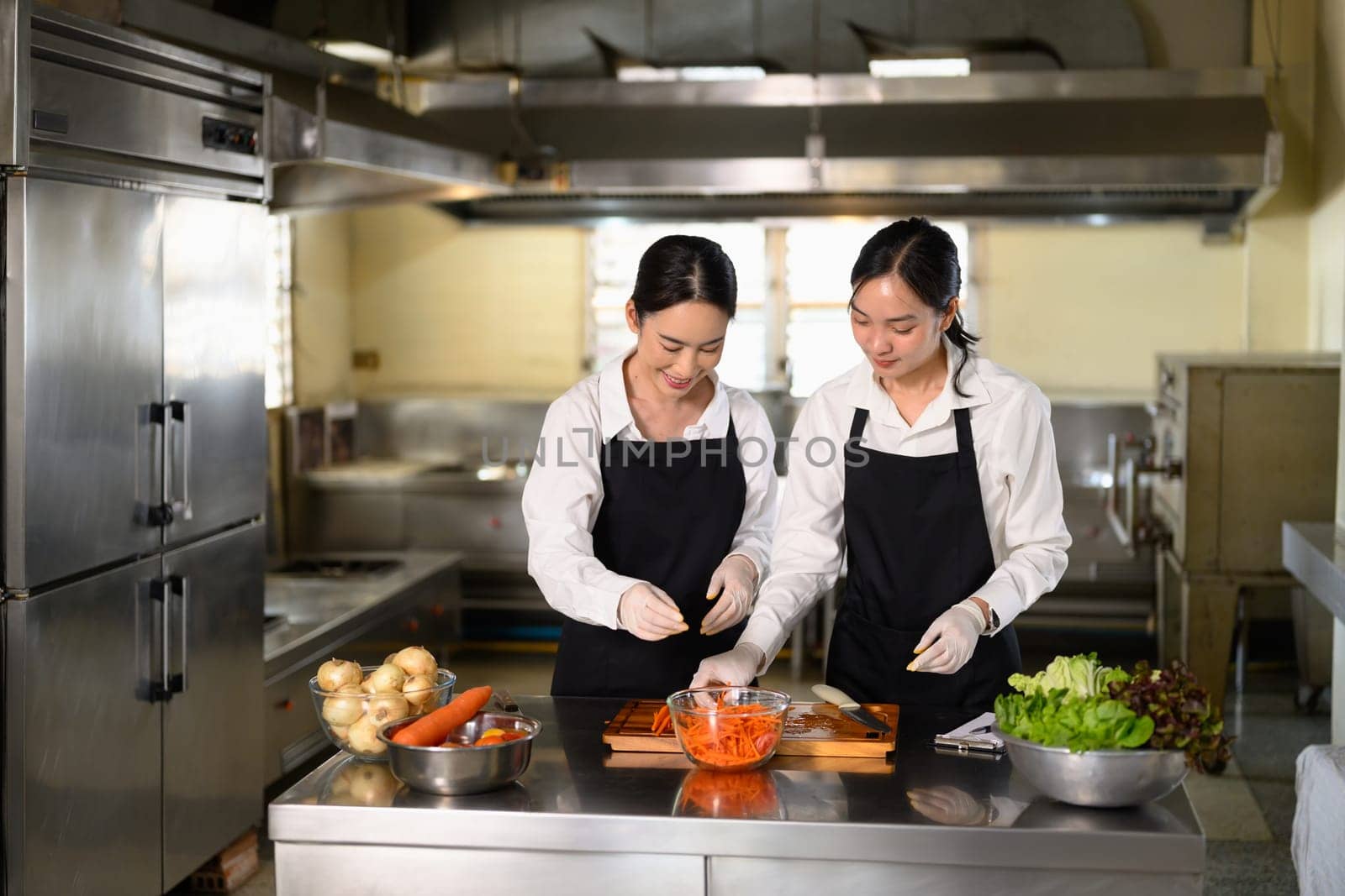 Culinary instructor guiding a student through carrot slicing during a practical cooking class.