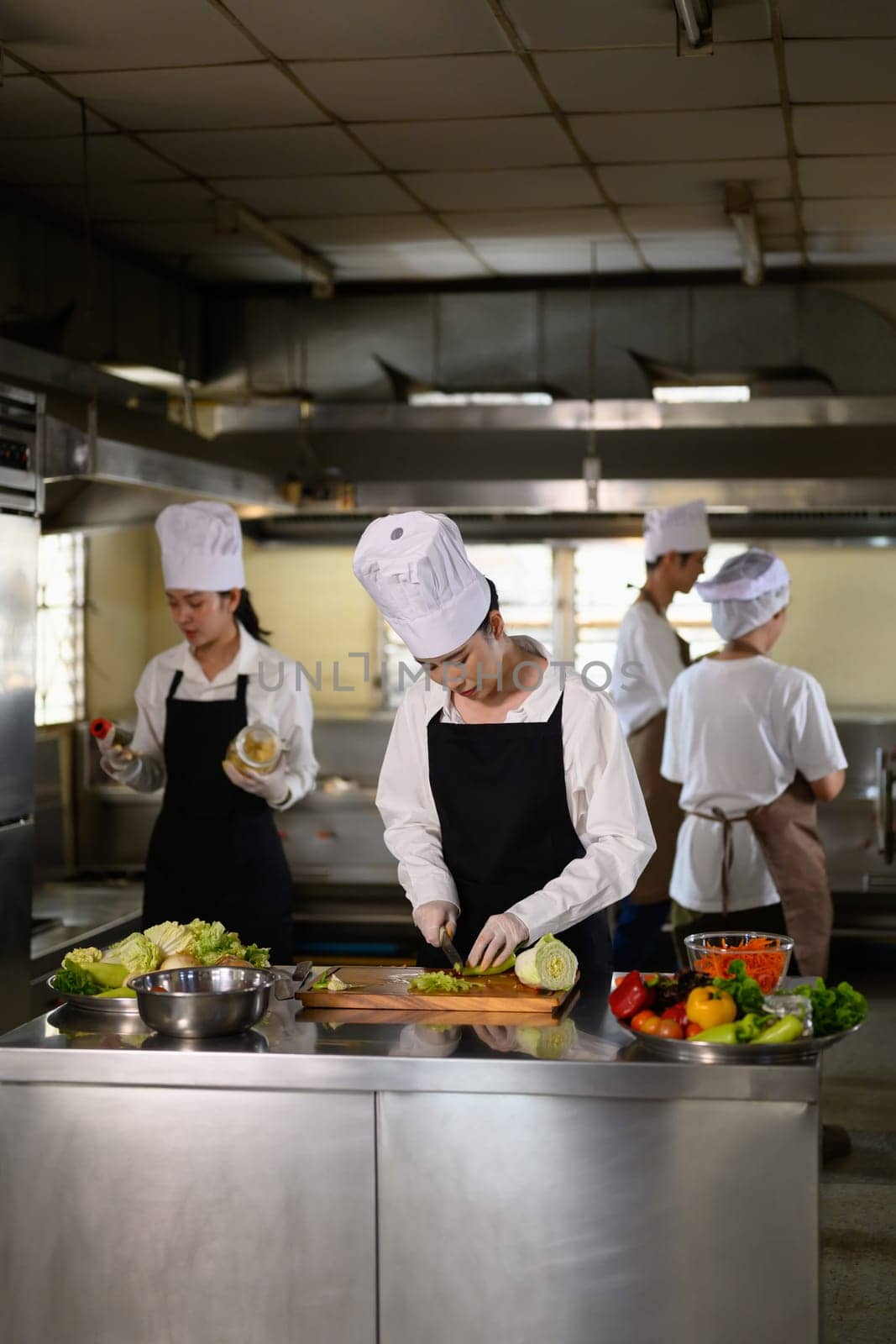 Chef apprentice working on vegetable preparation in a busy kitchen..