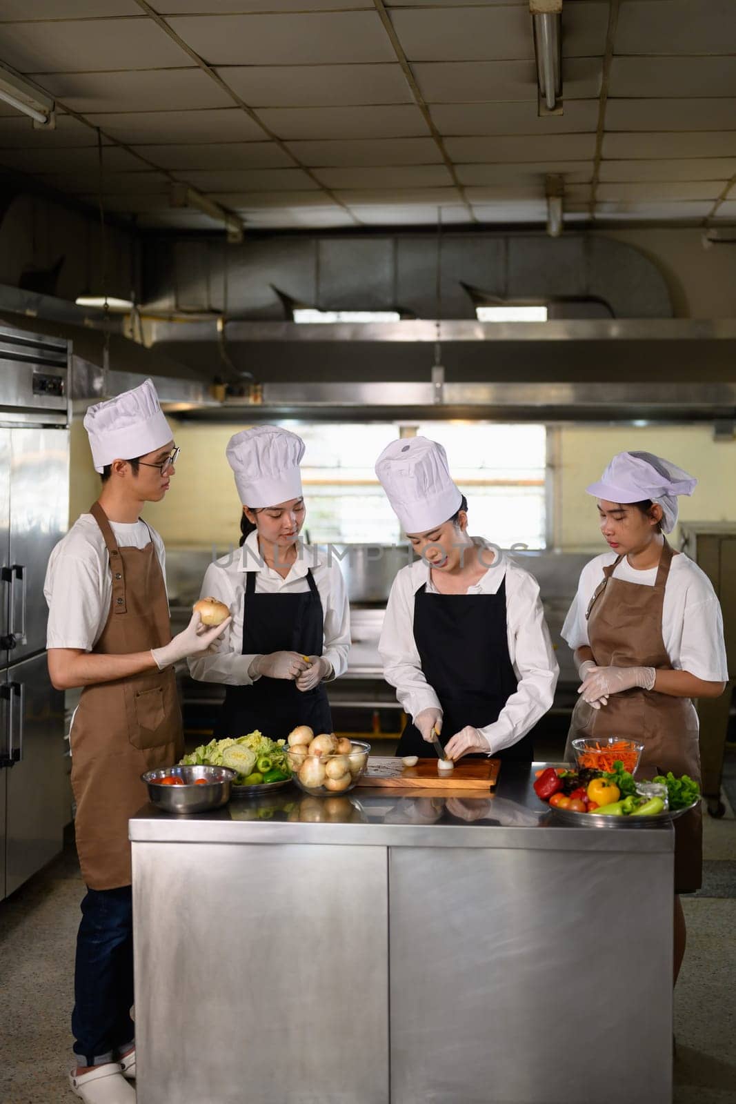 Cooking students attentively watching their teacher demonstrate food preparation techniques.