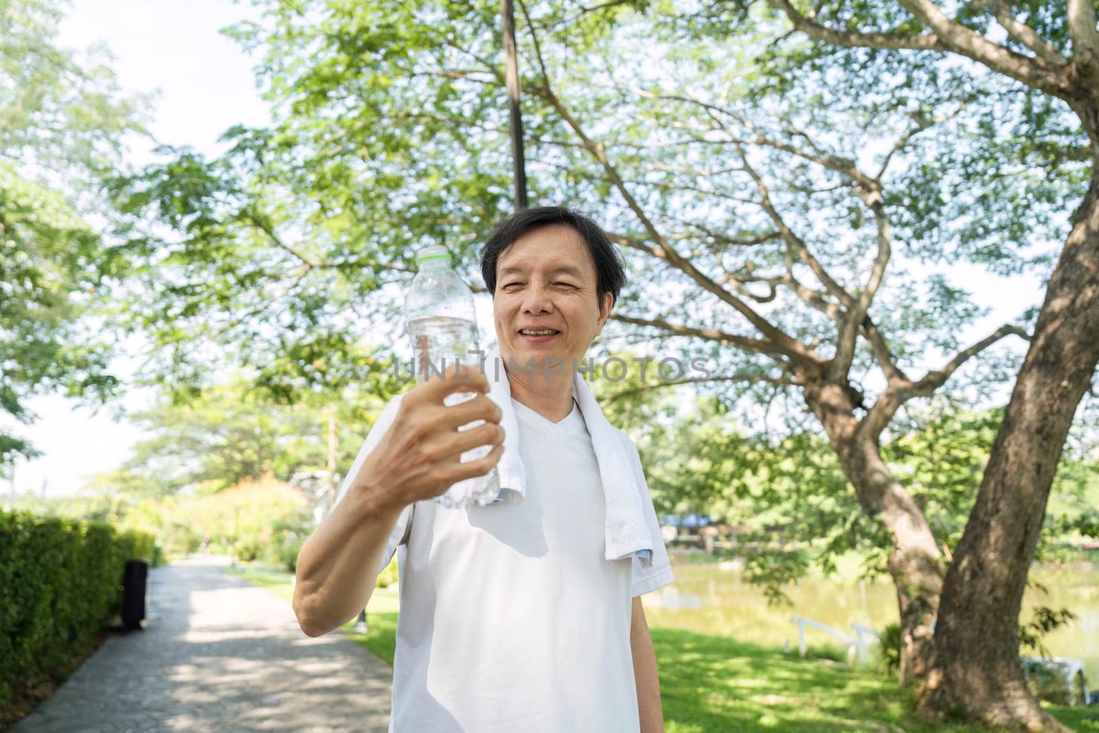 A joyful man smiles while holding a water bottle on his morning walk, representing wellness and a positive lifestyle.