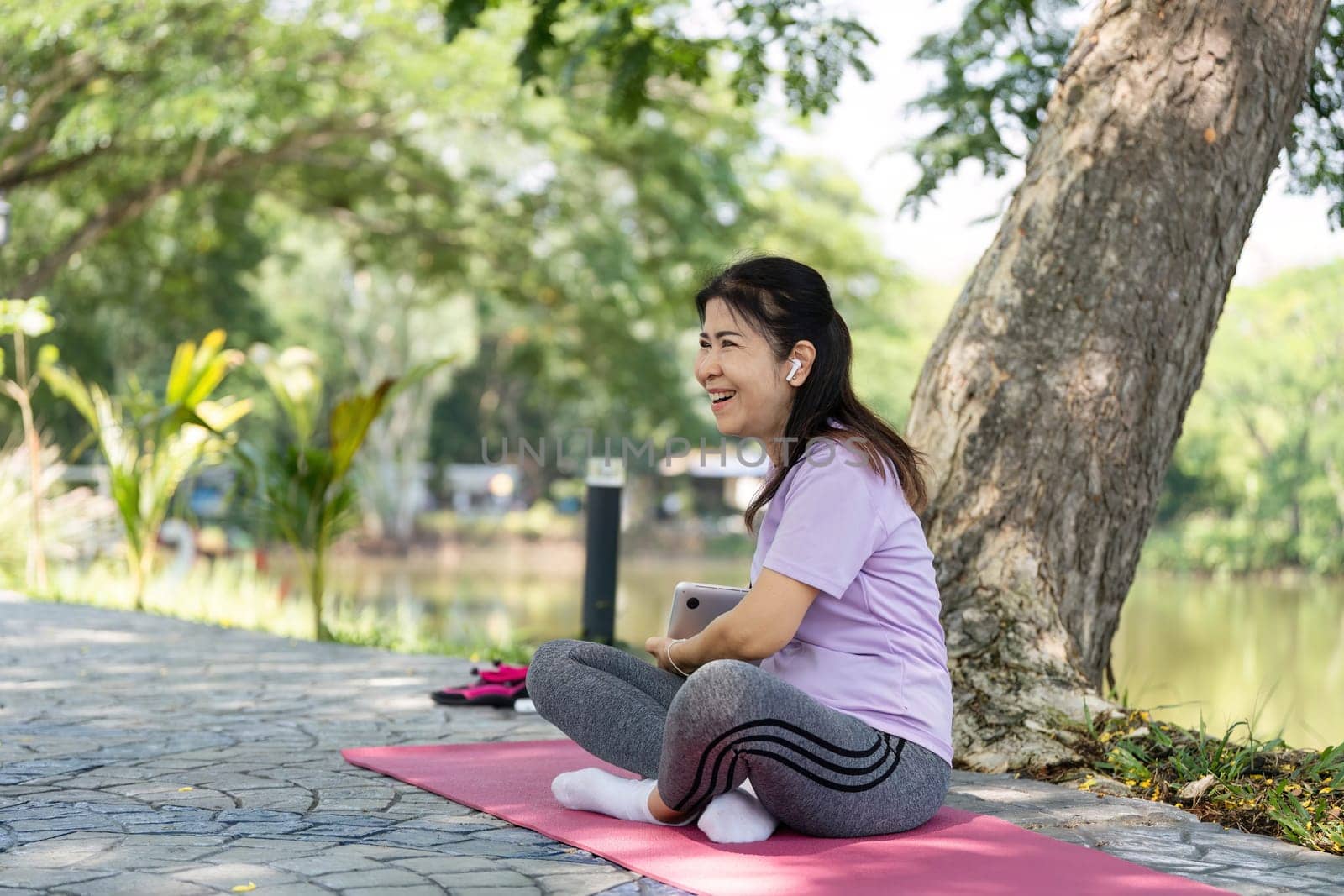 A joyful woman enjoys a moment of happiness on her yoga mat outdoors, embodying wellness and positivity in nature.